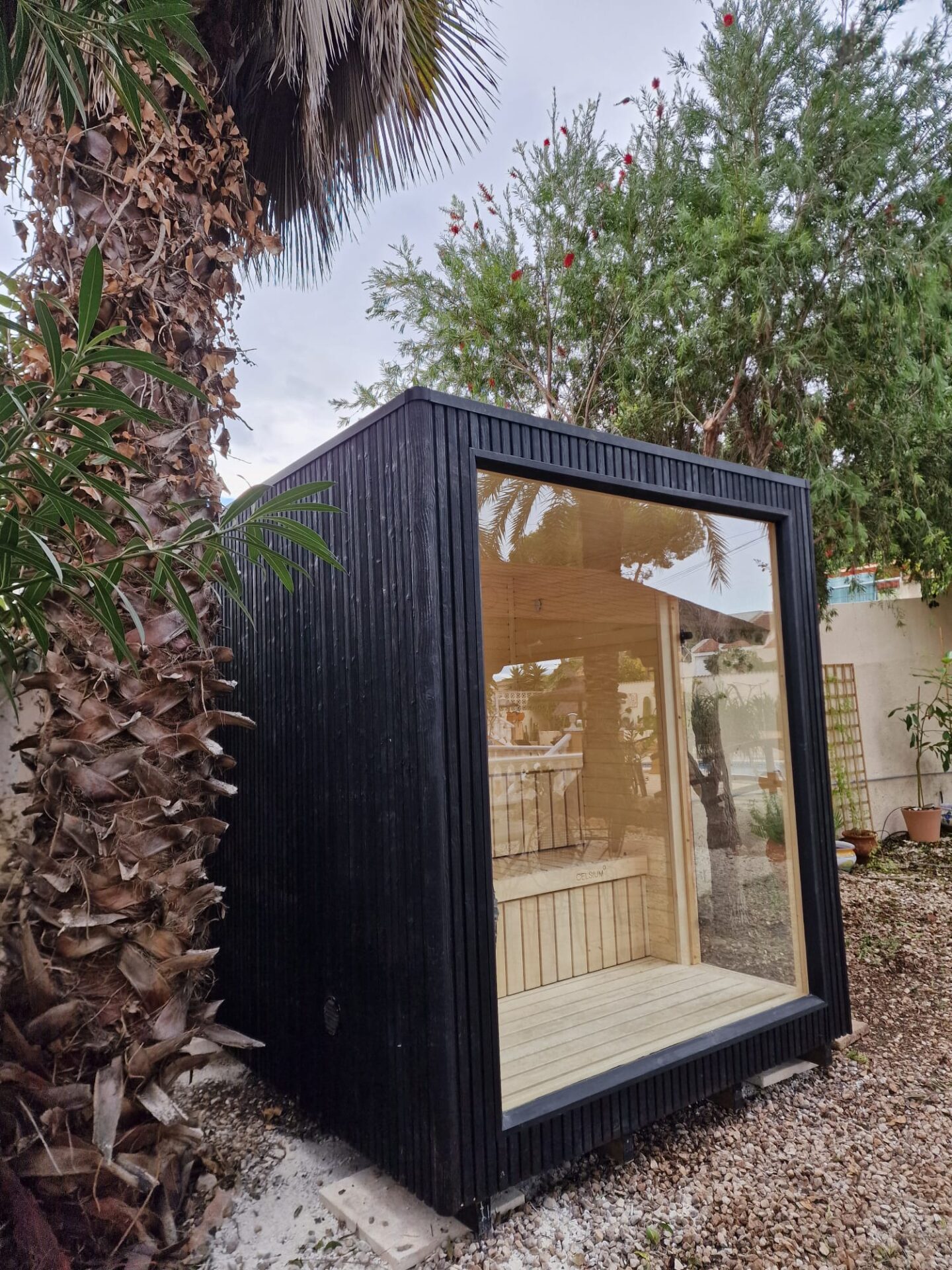 A modern Celsium Wellness sauna surrounded by lush greenery and calm outdoor living